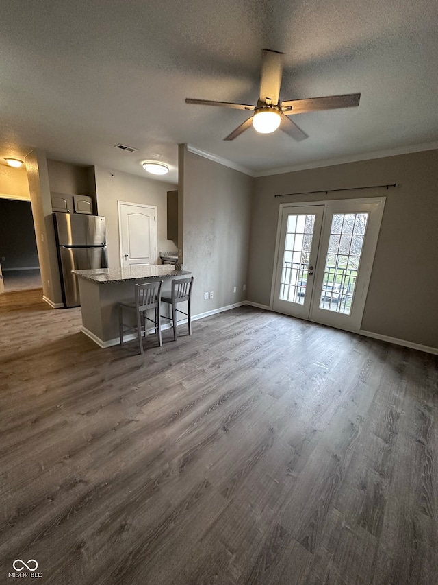 kitchen with stainless steel refrigerator, french doors, dark wood-type flooring, a kitchen breakfast bar, and a textured ceiling