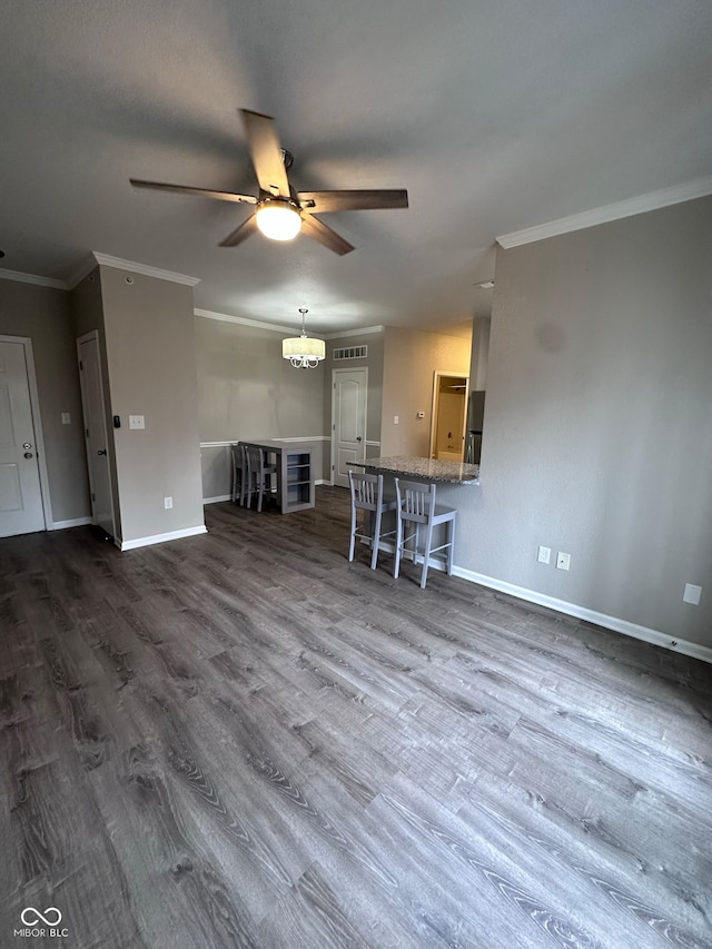 unfurnished living room with ceiling fan, crown molding, and dark wood-type flooring