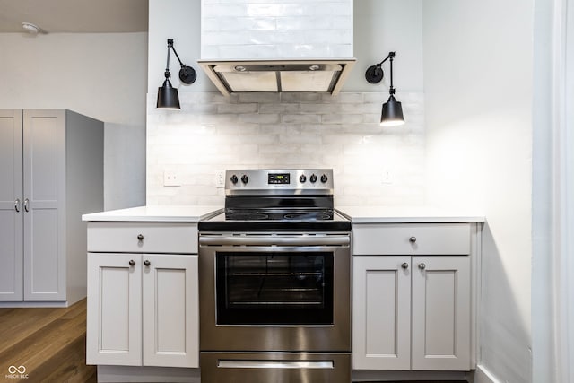 kitchen with decorative backsplash, dark hardwood / wood-style flooring, stainless steel range with electric stovetop, extractor fan, and hanging light fixtures