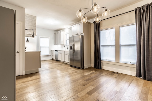 kitchen featuring hanging light fixtures, light wood-type flooring, and appliances with stainless steel finishes