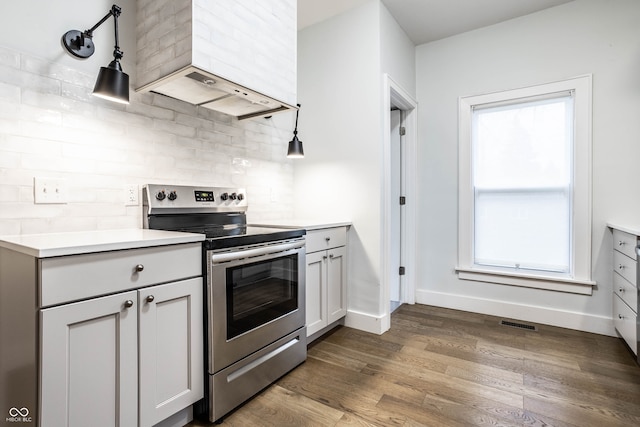 kitchen with dark hardwood / wood-style flooring, electric range, premium range hood, and gray cabinetry