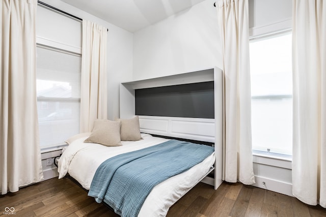 bedroom with dark hardwood / wood-style flooring and multiple windows