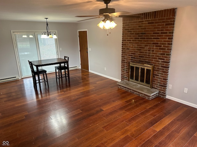 dining space featuring dark hardwood / wood-style flooring, ceiling fan with notable chandelier, and a brick fireplace