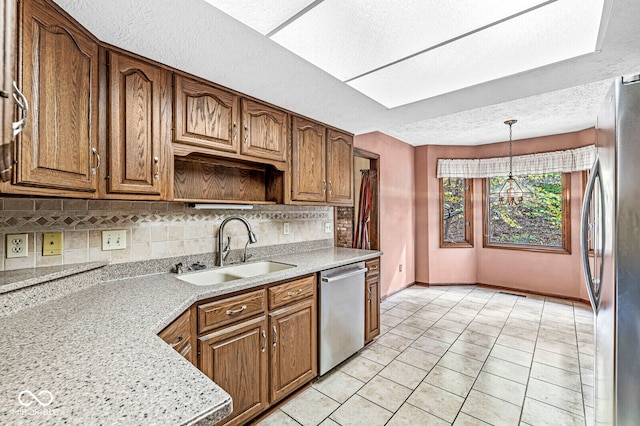 kitchen with sink, tasteful backsplash, decorative light fixtures, light stone counters, and stainless steel appliances