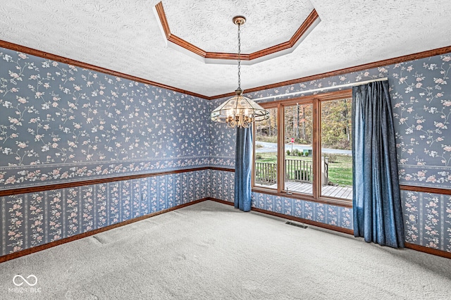 carpeted spare room with a textured ceiling, an inviting chandelier, and ornamental molding