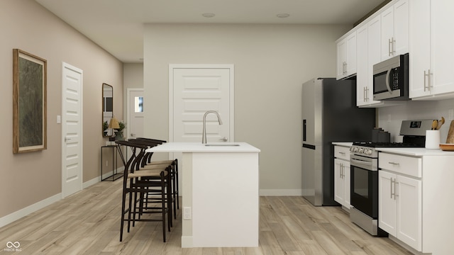 kitchen with a kitchen bar, sink, a kitchen island with sink, stainless steel appliances, and white cabinets