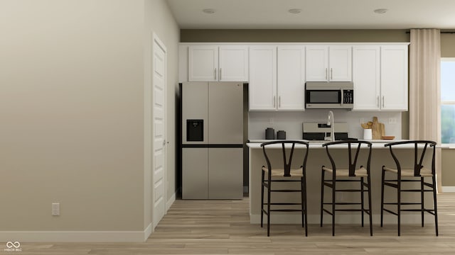 kitchen featuring tasteful backsplash, a breakfast bar area, stainless steel appliances, and white cabinetry