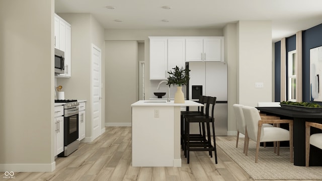 kitchen featuring light hardwood / wood-style floors, sink, white cabinetry, appliances with stainless steel finishes, and a kitchen breakfast bar