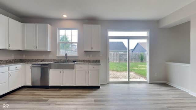 kitchen with light stone countertops, white cabinetry, dishwasher, sink, and light wood-type flooring