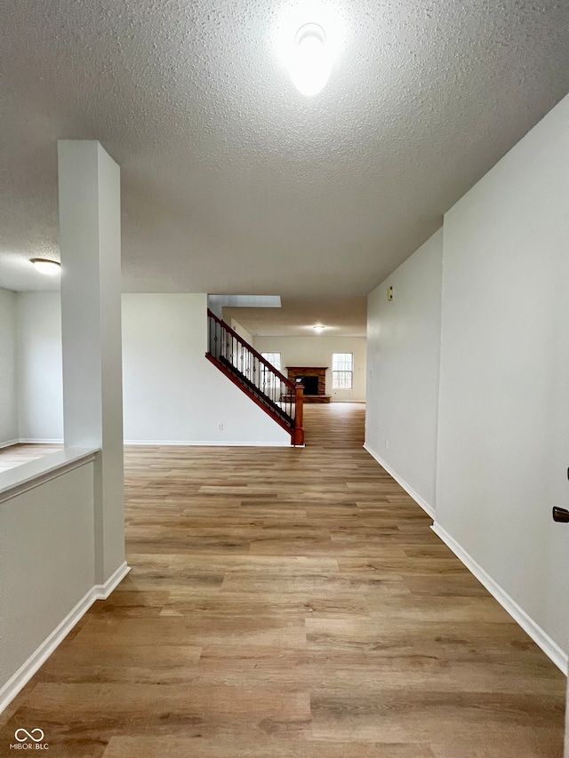 hall with light hardwood / wood-style floors and a textured ceiling