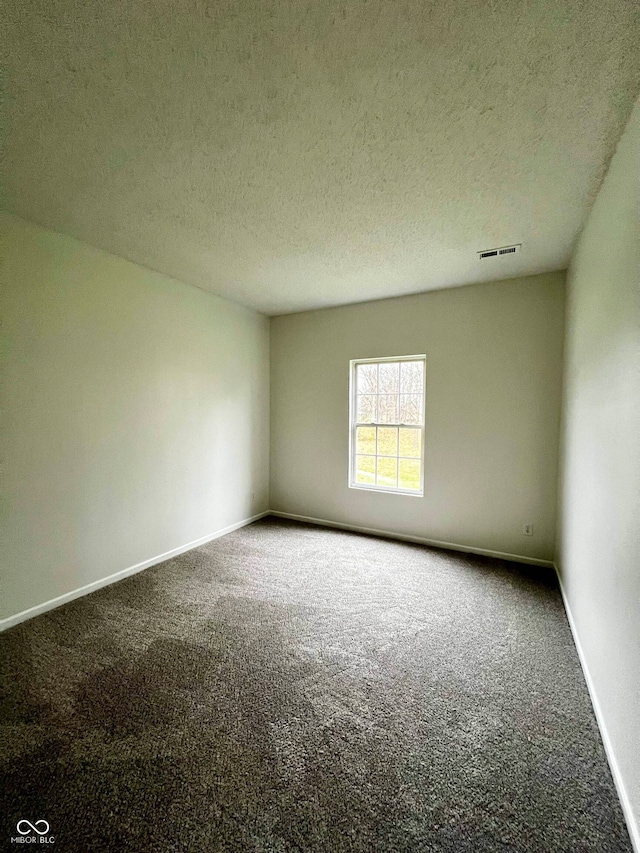 carpeted empty room with a textured ceiling