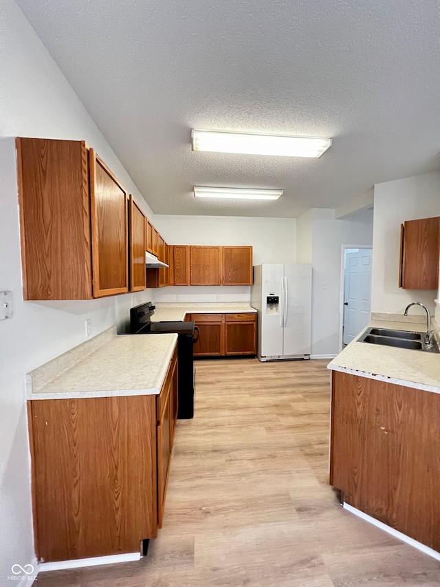 kitchen with electric range, white fridge with ice dispenser, sink, a textured ceiling, and light wood-type flooring