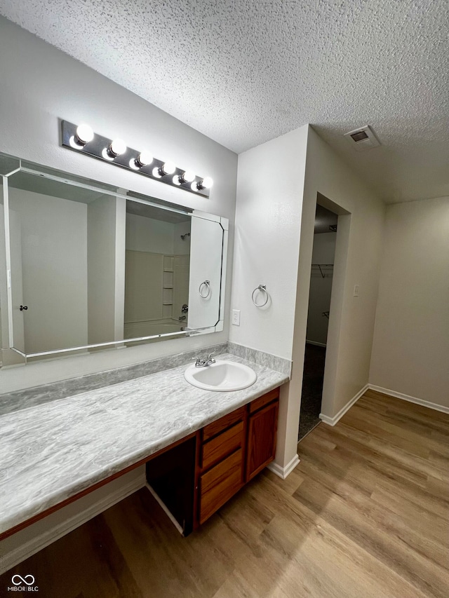 bathroom with hardwood / wood-style floors, vanity, and a textured ceiling