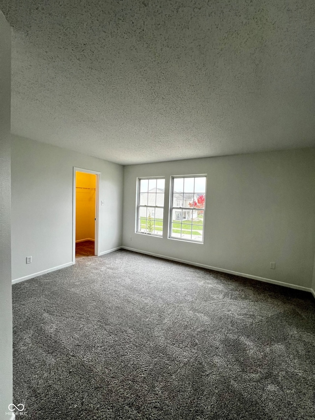 carpeted empty room with a textured ceiling