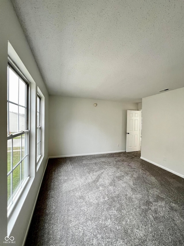 carpeted empty room featuring a textured ceiling