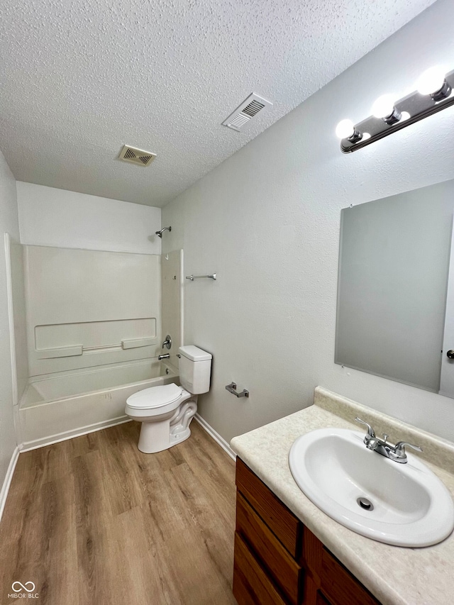 full bathroom with vanity, a textured ceiling, washtub / shower combination, hardwood / wood-style floors, and toilet