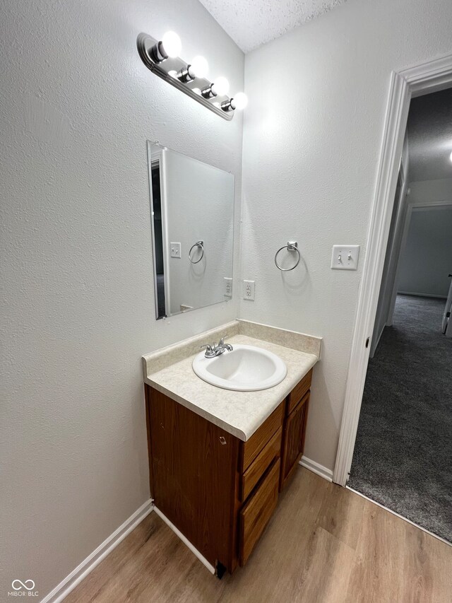 bathroom with wood-type flooring, vanity, and a textured ceiling