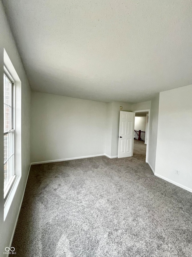 carpeted empty room featuring a textured ceiling