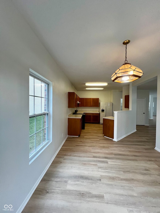 kitchen featuring white fridge with ice dispenser, pendant lighting, and light wood-type flooring