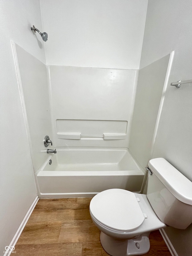 bathroom with washtub / shower combination, toilet, and wood-type flooring