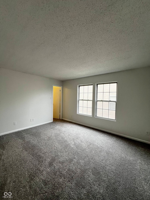 empty room with carpet floors and a textured ceiling