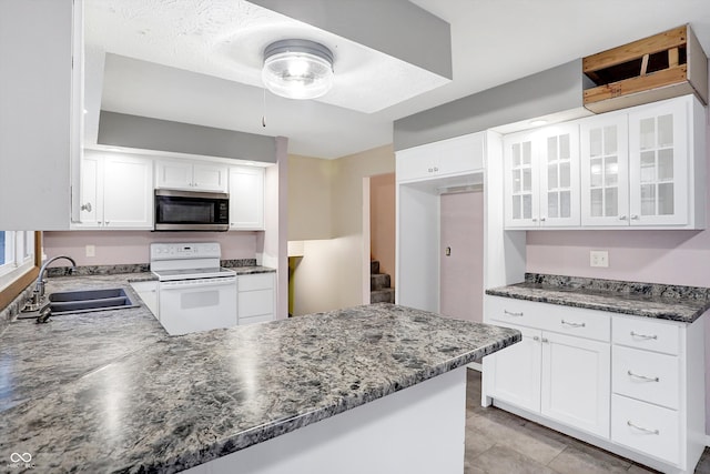 kitchen featuring sink, kitchen peninsula, dark stone counters, white cabinets, and white stove