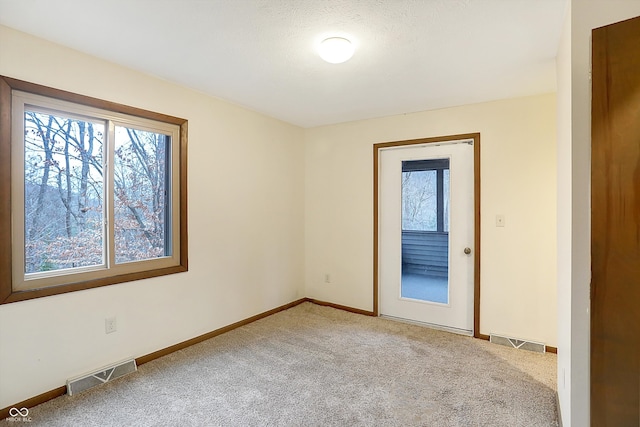 carpeted empty room with a textured ceiling