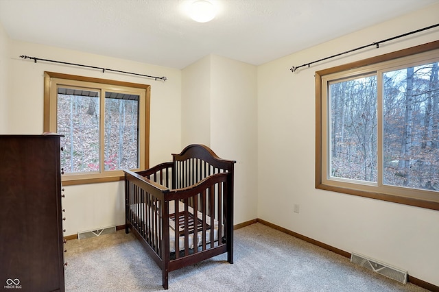 bedroom with light colored carpet, a crib, and multiple windows