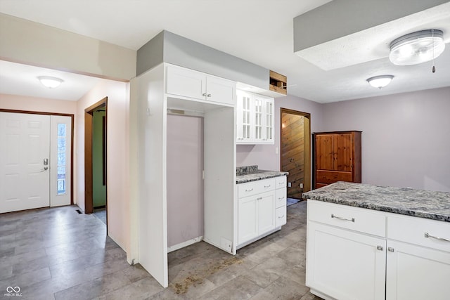 kitchen with white cabinetry and light stone counters