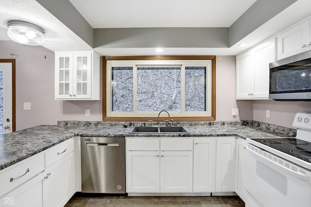 kitchen featuring appliances with stainless steel finishes, white cabinetry, dark stone countertops, and sink