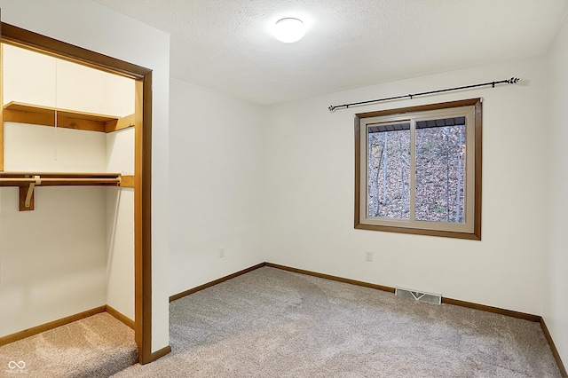 unfurnished bedroom with a textured ceiling, light colored carpet, and a closet