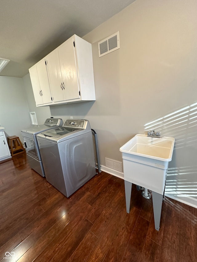 laundry area featuring washer and clothes dryer, dark wood-type flooring, and cabinets