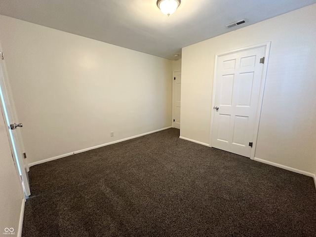 unfurnished bedroom featuring dark carpet and a closet