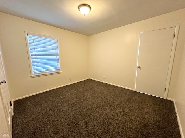 spare room with dark carpet