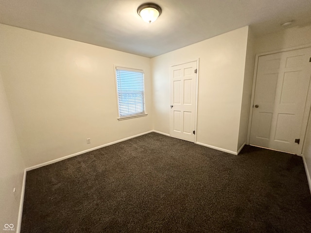 unfurnished bedroom featuring a closet and dark carpet