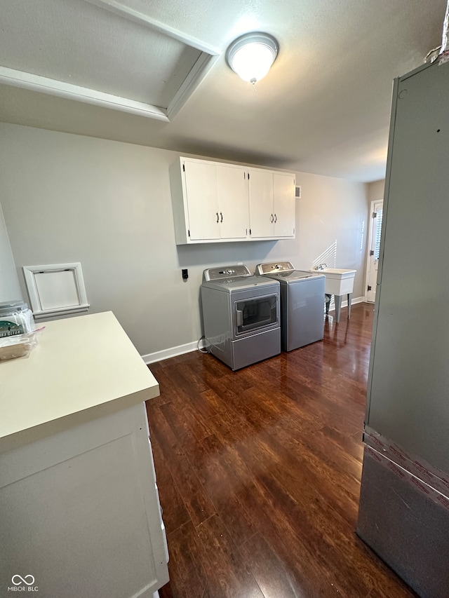 laundry room with washer and clothes dryer, dark hardwood / wood-style floors, cabinets, and sink