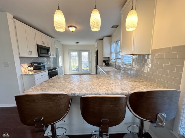 kitchen with kitchen peninsula, stainless steel appliances, sink, decorative light fixtures, and white cabinets