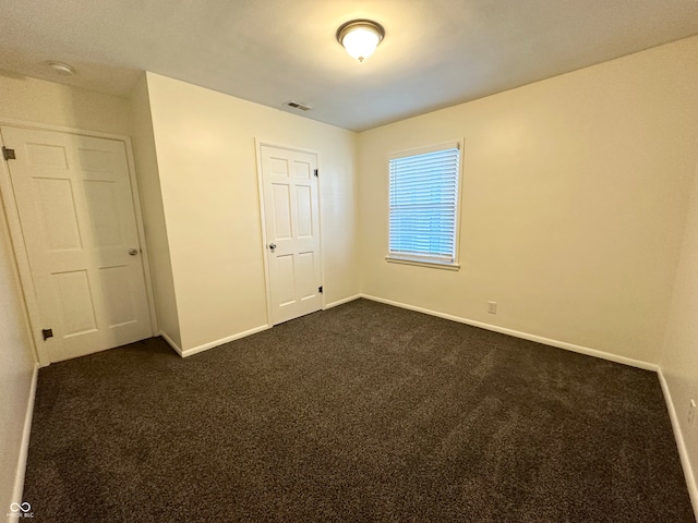 unfurnished bedroom with a closet and dark carpet