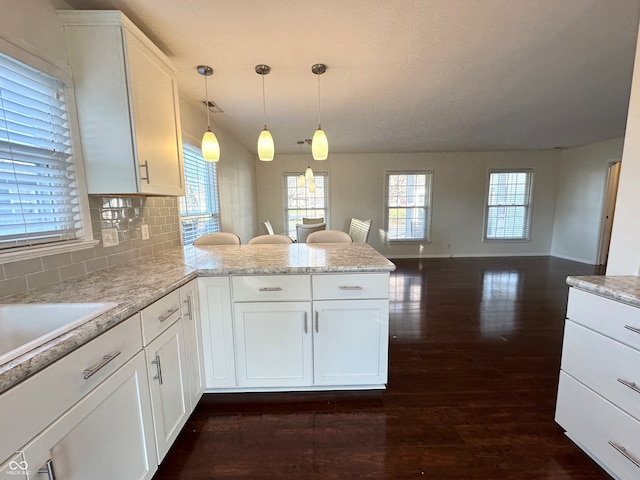 kitchen with white cabinets, decorative light fixtures, dark hardwood / wood-style flooring, and kitchen peninsula