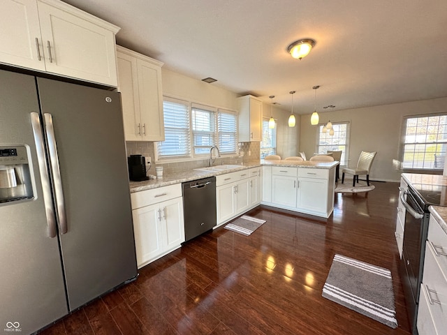 kitchen with kitchen peninsula, appliances with stainless steel finishes, decorative light fixtures, and plenty of natural light