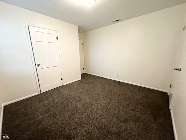 unfurnished bedroom with a closet and dark colored carpet