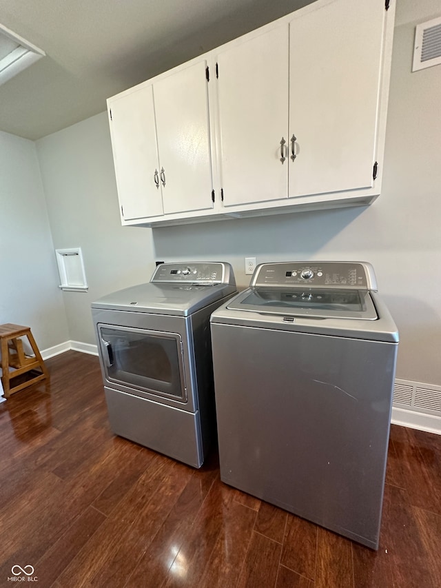 laundry room with washer and clothes dryer, dark hardwood / wood-style flooring, and cabinets