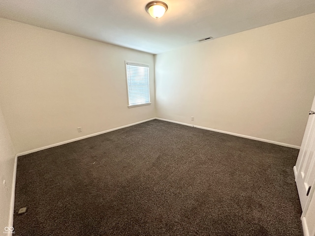 spare room with dark colored carpet