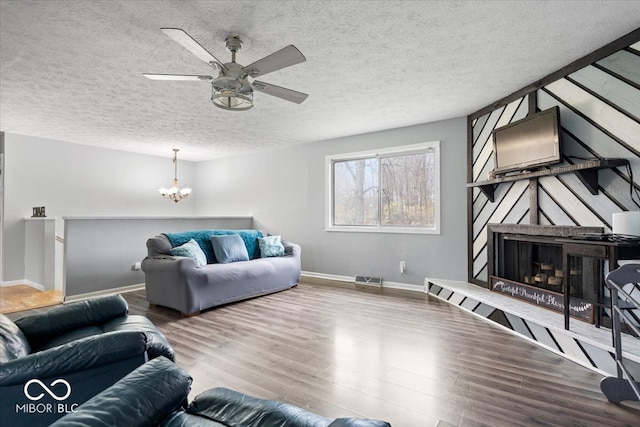 living room with hardwood / wood-style floors, ceiling fan with notable chandelier, and a textured ceiling