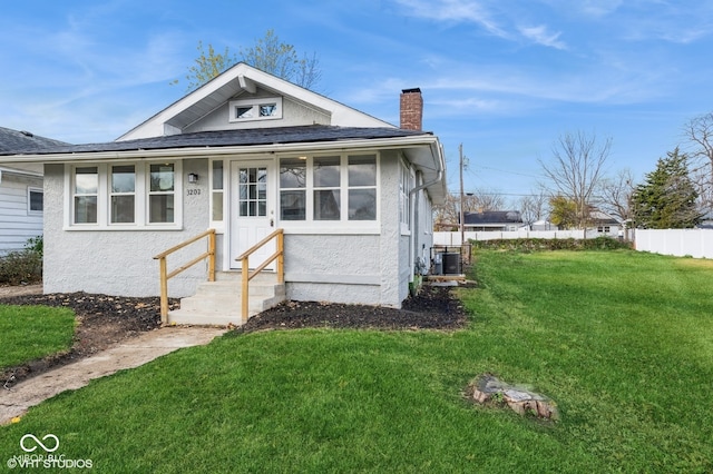 bungalow with a front lawn and central air condition unit