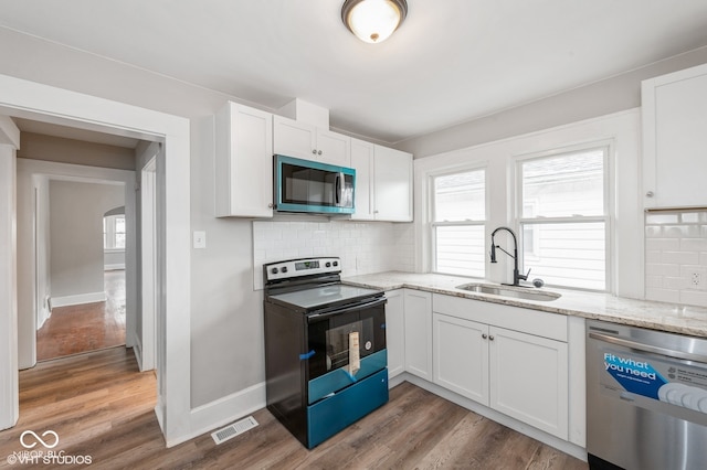 kitchen with backsplash, sink, white cabinets, and stainless steel appliances