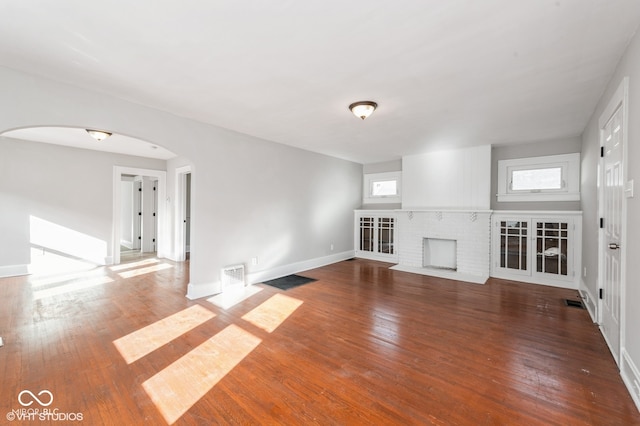 unfurnished living room with a fireplace, wood-type flooring, and plenty of natural light