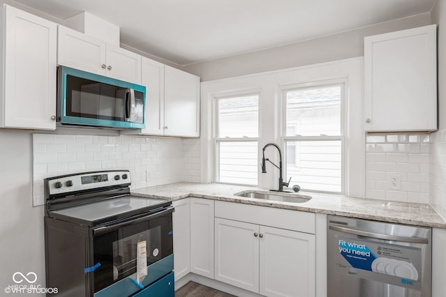 kitchen featuring sink, light stone counters, decorative backsplash, white cabinets, and appliances with stainless steel finishes