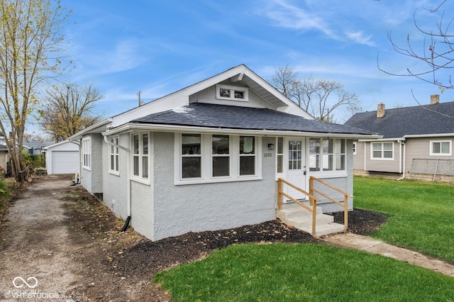 view of front of property featuring a garage, an outbuilding, and a front lawn