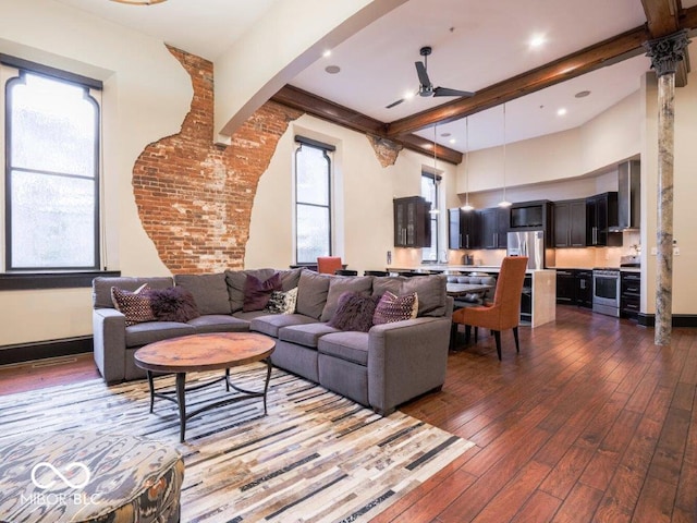 living room with beamed ceiling, dark hardwood / wood-style floors, ceiling fan, and a wealth of natural light